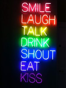 Neon letters in de kleuren van de regenboog Smile laugh talk drink shout eat kiss