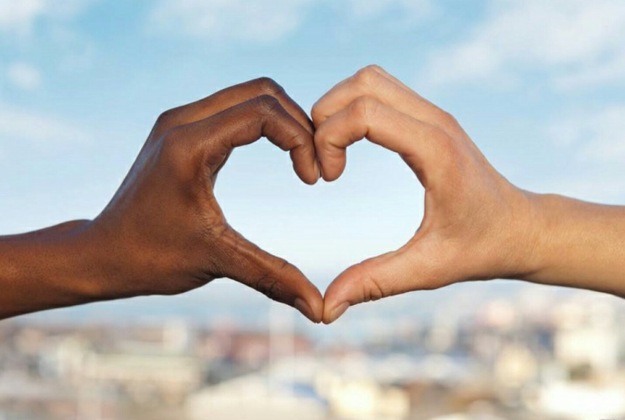 Een zwarte en een witte hand vormen samen een hart.