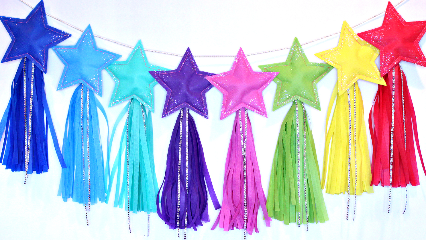 Christmas stars of soft fabric in rainbow colours hanging in line. 